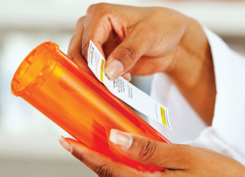 Pharmacist applying label to pill bottle